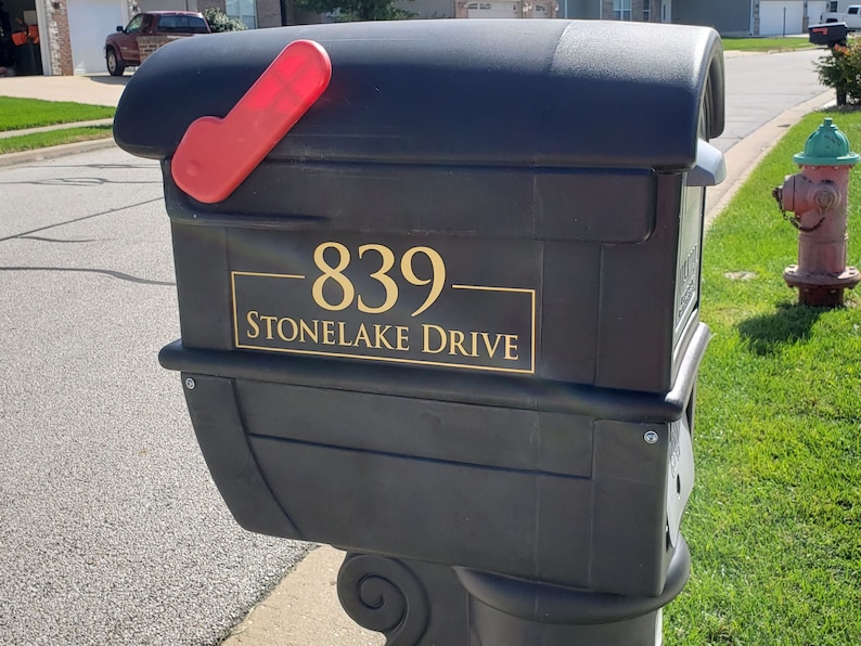 Puede incluir: Buz&oacute;n negro con una bandera roja y una placa dorada que dice "839- Stonlake Drive".