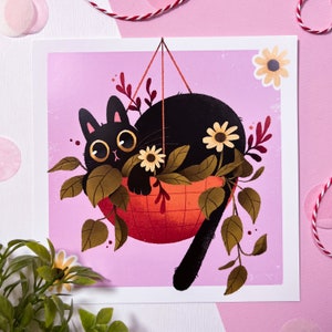 Könnte beinhalten: Eine schwarze Katze mit gelben Augen sitzt in einem hängenden orangefarbenen und weißen Blumentopf mit grünen Blättern und weißen Blüten. Die Katze schaut den Betrachter an. Der Hintergrund ist rosa.