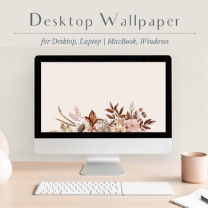 May include: A desktop computer screen displaying a floral wallpaper with a light beige background. The wallpaper features a cluster of dried flowers and leaves in shades of brown, pink, and white. The computer is on a wooden desk with a white keyboard, a beige mug, and a notebook.