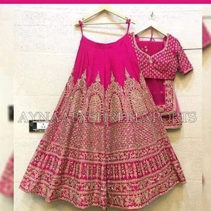 May include: A pink and gold embroidered lehenga with a matching choli. The lehenga is a traditional Indian garment worn by women for special occasions.