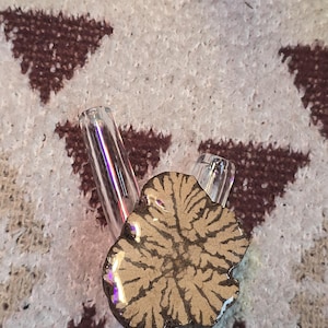 May include: A ceramic pipe with a brown and white design. The pipe has two glass tubes attached to it.