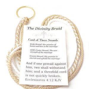 May include: A Divinity Braid, a cord of three strands, with a gold ring. The cord is made of beige and white braided rope. A card with text about the cord's symbolism is attached. The text includes a Bible verse from Ecclesiastes.