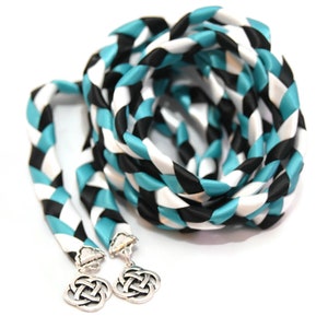 May include: A braided cord with black, white, and teal stripes. The cord has two silver Celtic knot charms attached to the ends.