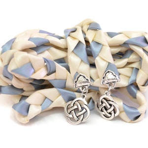 May include: A braided wedding cord made of ivory and light blue satin ribbon with silver Celtic knot charms.