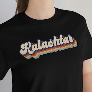 May include: A black t-shirt with a retro-style graphic that says "Kalashitar" in rainbow colors.