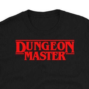 May include: Black t-shirt with a red graphic that says "DUNGEON MASTER" in a style reminiscent of the Stranger Things logo.