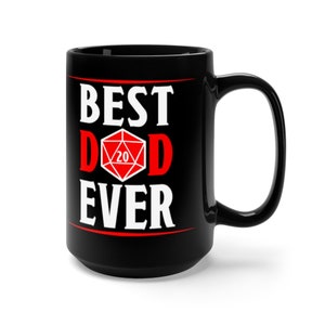 以下が含まれることがあります： 黒色のセラミック製のコーヒーカップで、白い文字で「BEST D20D EVER」と書かれています。「D」は大きく赤色で、その間に赤い20面ダイスがあります。