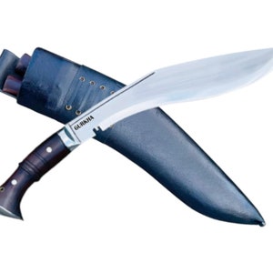 May include: A silver-colored Gurkha knife with a dark brown wooden handle and a black leather sheath. The knife has a curved blade and a serrated edge. The sheath has a strap and a buckle.