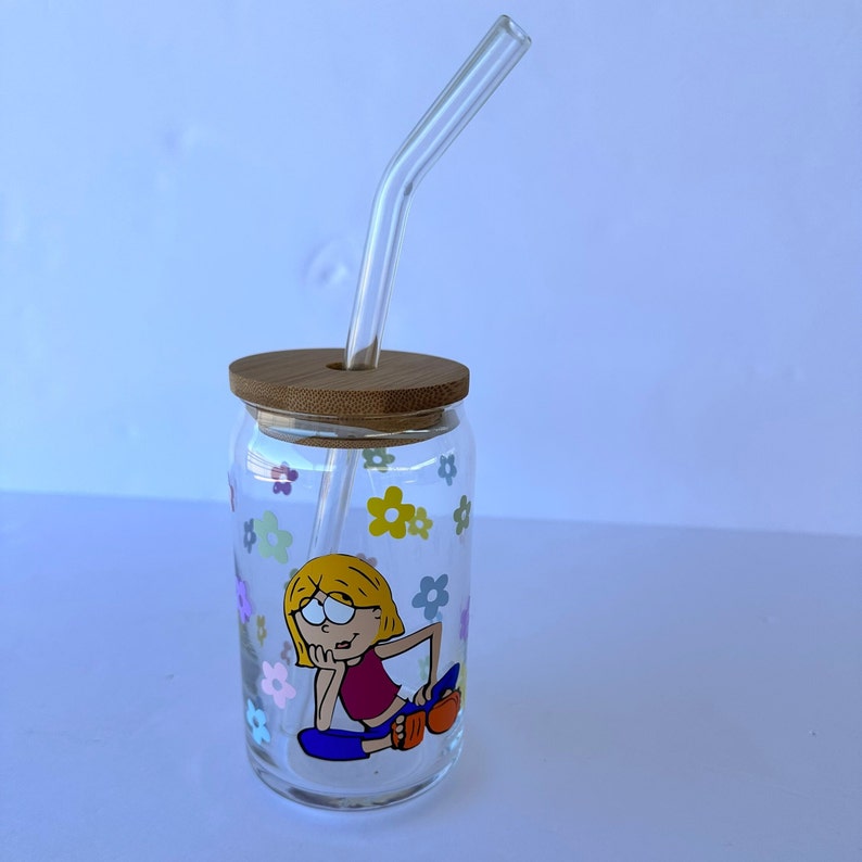 May include: A clear glass jar with a bamboo lid and a glass straw. The jar has a cartoon illustration of a girl with flowers around the jar.