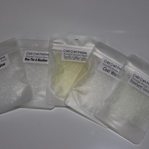 May include: Five small clear plastic bags filled with white and yellow scented diffuser beads. The bags are labeled with the scents: Black Ice, Bow Ties & Bourbon, Vanilla Coffee Latte, Cool Water, and Strawberry Coconut.