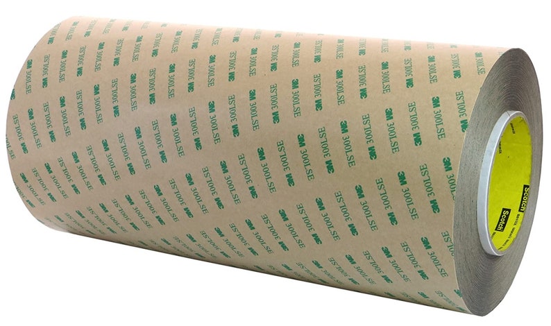 K&ouml;nnte beinhalten: Eine Rolle braunes Klebeband mit gr&uuml;nem Text, der "3M 300LSE" lautet, und einem gelben Etikett mit der Aufschrift "Scotch".