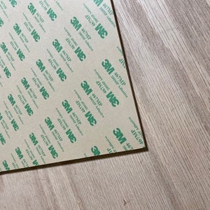 May include: A sheet of brown adhesive tape with a repeating pattern of green text that reads "3M 467MP 200MP Adhesive".