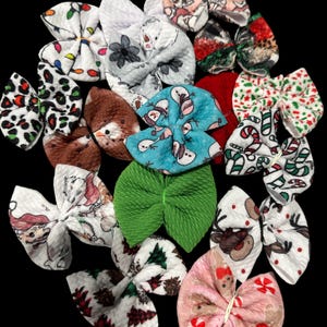 May include: A collection of 15 Christmas-themed hair bows in various colors and patterns, including red, green, white, blue, and pink. The bows feature designs such as snowmen, reindeer, candy canes, and Christmas trees.