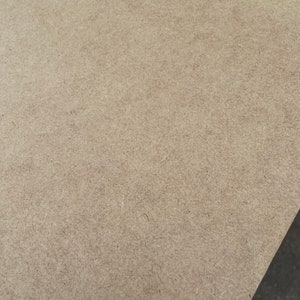 May include: A close-up of a light brown, textured surface. The surface is made of wood and has a rough, grainy texture.