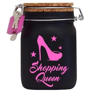 Puede incluir: Un tarro negro con cierre de llave con un dise&ntilde;o de zapato de tac&oacute;n alto rosa y estrellas. El tarro tiene una tapa de corcho y un cierre de metal. El texto "Shopping Queen" est&aacute; escrito en rosa en el tarro.