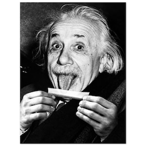 May include: A black and white portrait of Albert Einstein with his tongue extended, holding a small rectangular white paper strip between his fingers. He has messy hair, a mustache, and is wearing a dark coat with a scarf around his neck.