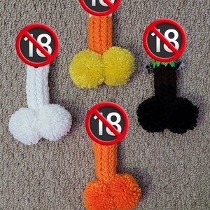 May include: Five knitted golf club head covers with pom-poms. The covers are in various colors, including orange, yellow, white, and black. Each cover has a red circle with a diagonal line through it and the number 18.