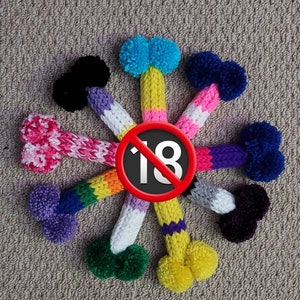 May include: A group of eight knitted golf club head covers in various colors, including pink, purple, blue, green, yellow, black, and white. The covers are arranged in a circle around a red circle with a diagonal line through it and the number 18 inside.