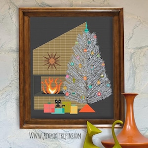 Puede incluir: Un bordado enmarcado que representa una escena navideña moderna de mediados de siglo. Un árbol de Navidad plateado está adornado con adornos coloridos. Una chimenea con un diseño de sol y un gato negro con regalos están en primer plano. La dirección del sitio web www.atomictikipins.com está en la parte inferior.