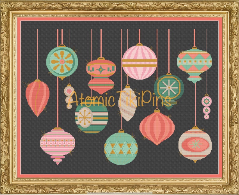 May include: A framed cross-stitch artwork featuring a collection of retro Christmas ornaments in shades of pink, teal, and gold against a dark gray background. The text "Atomic TriPings" is visible. The ornaments have various geometric and starburst designs.