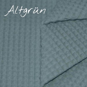 May include: A close-up of a blue waffle weave fabric. The fabric is folded in half, showing the texture of the weave. The word "Altgr&uuml;n" is written in white on the fabric.