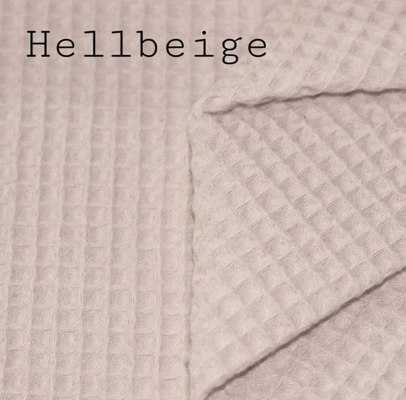May include: A close-up of a light beige waffle weave fabric. The fabric is folded in half, showing the texture of the weave. The text "Hellbeige" is printed in black at the top of the image.