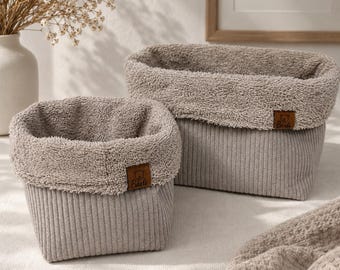 May include: Two rectangular storage baskets made of light gray corduroy fabric with a textured, fuzzy interior lining. Each basket features a small brown leather-like tag on the front with the text Barli and a bear icon embossed on the surface.