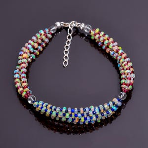 Puede incluir: Una pulsera de múltiples hilos con una mezcla de cuentas de ópalo coloridas, cuentas rojas oscuras y pequeñas cuentas azules. La pulsera se asegura con un cierre plateado y una cadena ajustable. Las cuentas están ensartadas para crear un efecto en capas.