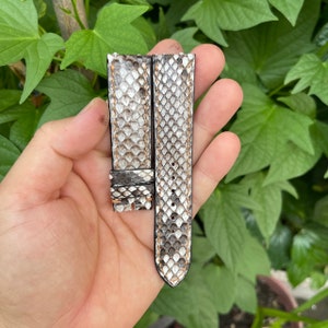 Könnte beinhalten: Zwei Uhrenarmbänder aus weißem und grauem Schlangenleder mit braunen Nähten. Die Armbänder sind 20 mm breit und haben einen Schließenverschluss.