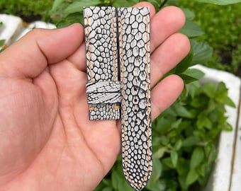 Könnte beinhalten: Ein weiß-schwarzes Armband aus Leder mit einem strukturierten Muster. Das Armband hat ein hellorangenes Nähtdetail.