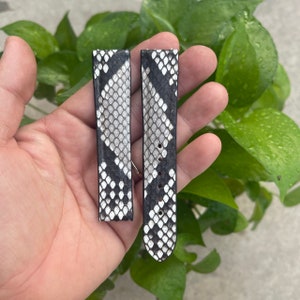Peut inclure: Deux bracelets de montre en peau de serpent noir et blanc. Les bracelets sont en véritable peau de serpent et présentent un motif noir et blanc.