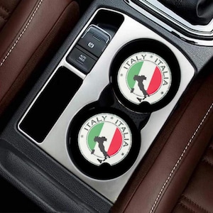 May include: Two circular car cup holder coasters featuring the Italian flag in green, white, and red. A black silhouette of the Italian peninsula is centered on each coaster. The text ITALY and ITALIA is printed in black along the circular border.