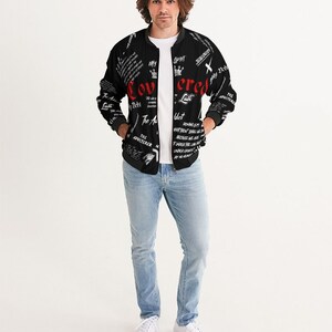 May include: A black bomber jacket with a white and red print. The print includes the words "Covered" and "Lust" in red. The jacket has a zipper closure and two pockets.