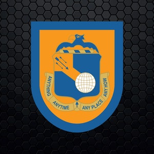 Puede incluir: Un escudo azul y dorado con un globo terráqueo, flechas y un pájaro. El escudo tiene el texto "Anything Anytime Any Place Any How" alrededor.