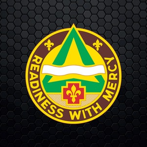 Op de afbeelding: Een rond embleem in geel en groen met een bruine rand. Het embleem toont een groene driehoek met een witte banner en een rood kruis met een fleur-de-lis. De tekst "READINESS WITH MERCY" staat rond het embleem.
