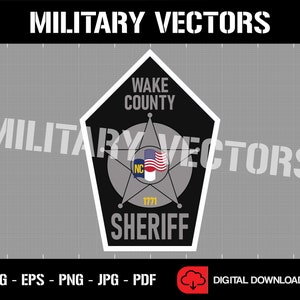 May include: A black and white badge with a five-pointed star in the centre. The badge has the text "WAKE COUNTY SHERIFF" and "1771" on it. The star has a small American flag and a blue and yellow state flag on it.