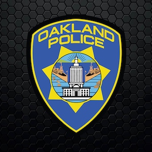 Könnte beinhalten: Ein blaues und goldenes Abzeichen der Polizei von Oakland mit einem Stern und einem Gebäude in der Mitte.