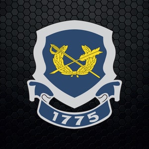 Puede incluir: Un escudo azul y blanco con una corona de laurel dorada y espadas cruzadas. El escudo tiene el año 1775 impreso.
