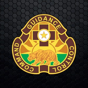 Op de afbeelding: Een gouden en bruin embleem met de woorden "Guidance Command Control" rond een bruin kruis met een witte ster in het midden. Een bruine beer staat op een groen en geel veld onder het kruis.