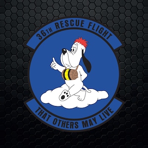 Op de afbeelding: Een rond blauw en wit embleem met de tekst "36th Rescue Flight That Others May Live". Een cartoonhond met een vat vastgebonden aan zijn borst zit op een wolk.