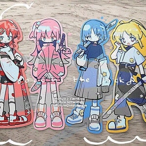 Puede incluir: Cuatro pegatinas de personajes de estilo anime de colores con diferentes peinados y ropa. Los personajes sostienen espadas y tienen diferentes expresiones en sus caras. Las pegatinas están sobre una superficie de madera.