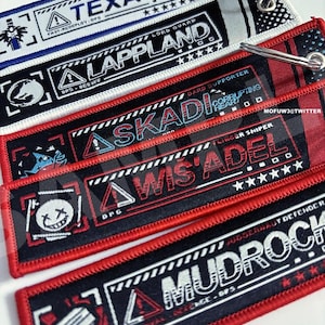 May include: Five black and red keychains with white text and graphics. The keychains feature the words "Texas", "Lappland", "Skadi", "Wis Adel", and "Mudroch".