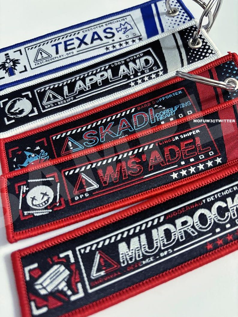 May include: Five black and red keychains with white text and graphics. The keychains feature the words "Texas", "Lappland", "Skadi", "Wis Adel", and "Mudroch".