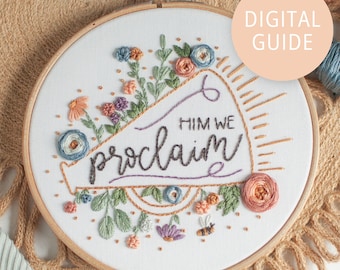 May include: Embroidered hoop art with a white background featuring a megaphone with the text "Him We Proclaim" and floral embellishments. The hoop is made of wood and has a brown finish. The image includes the text "Digital Guide".
