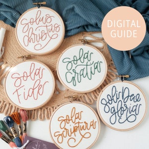 May include: Five embroidery hoops with different coloured embroidery floss. The hoops are white with brown wooden frames. The embroidery reads "Sola Christus", "Sola Fide", "Sola Gratia", "Sola Scriptura", and "Soli Deo Gloria".