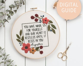 May include: Embroidered hoop art with a quote by Augustine: "You have made us for yourself and our heart is restless until it rests in you." The hoop is decorated with red, orange, and green floral embroidery.