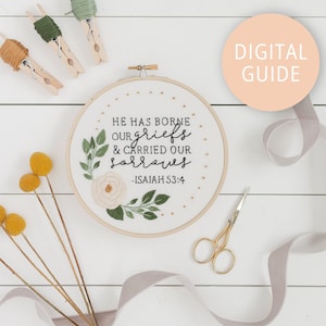 May include: White embroidery hoop with a floral design and the text "He has borne our griefs & carried our sorrows - Isaiah 53:4".