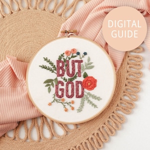 May include: Embroidered hoop art featuring the phrase "BUT GOD" in burgundy lettering surrounded by green and orange floral embroidery on a white background.