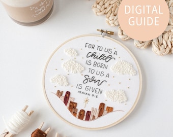 May include: A white embroidery hoop with a beige background. The hoop features a hand-stitched design of a cityscape with clouds and the text "FOR TO US A child IS BORN TO US A Son IS GIVEN ISAIAH 9:6".