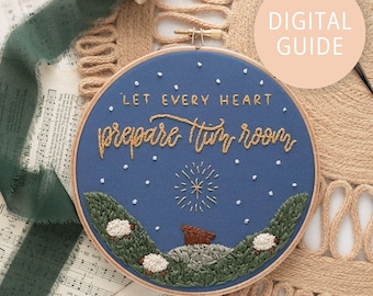 May include: A round embroidery hoop with a blue fabric background. The text "LET EVERY HEART prepare him room" is stitched in gold thread. The design includes embroidered sheep, hills, and a starburst. A "DIGITAL GUIDE" label is visible.